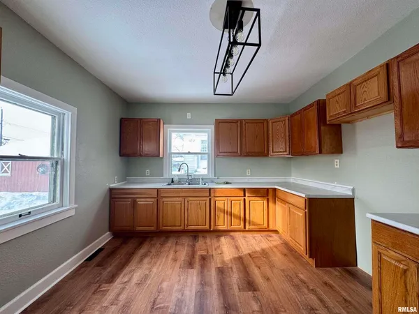 a large kitchen with stainless steel appliances granite countertop a sink stove refrigerator and wooden floor