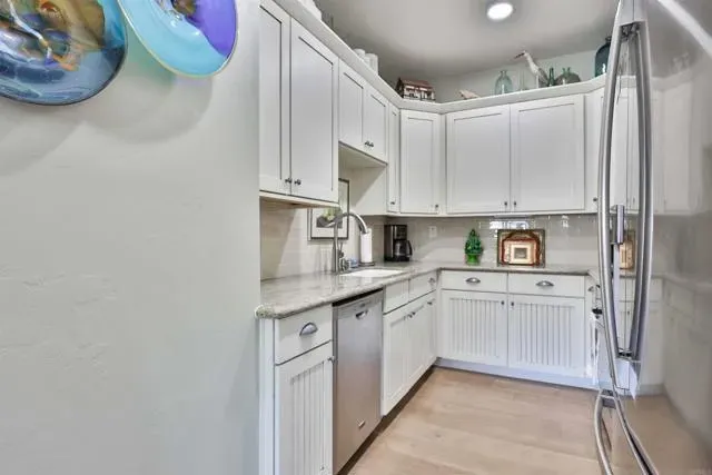 a kitchen with granite countertop a sink stainless steel appliances and white cabinets