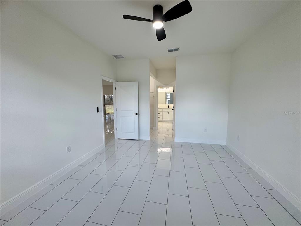 12970 Southwest 43rd Ave Road Ocala, FL 34473 - Photo 13 of 44 an empty room with white walls and ceiling fan