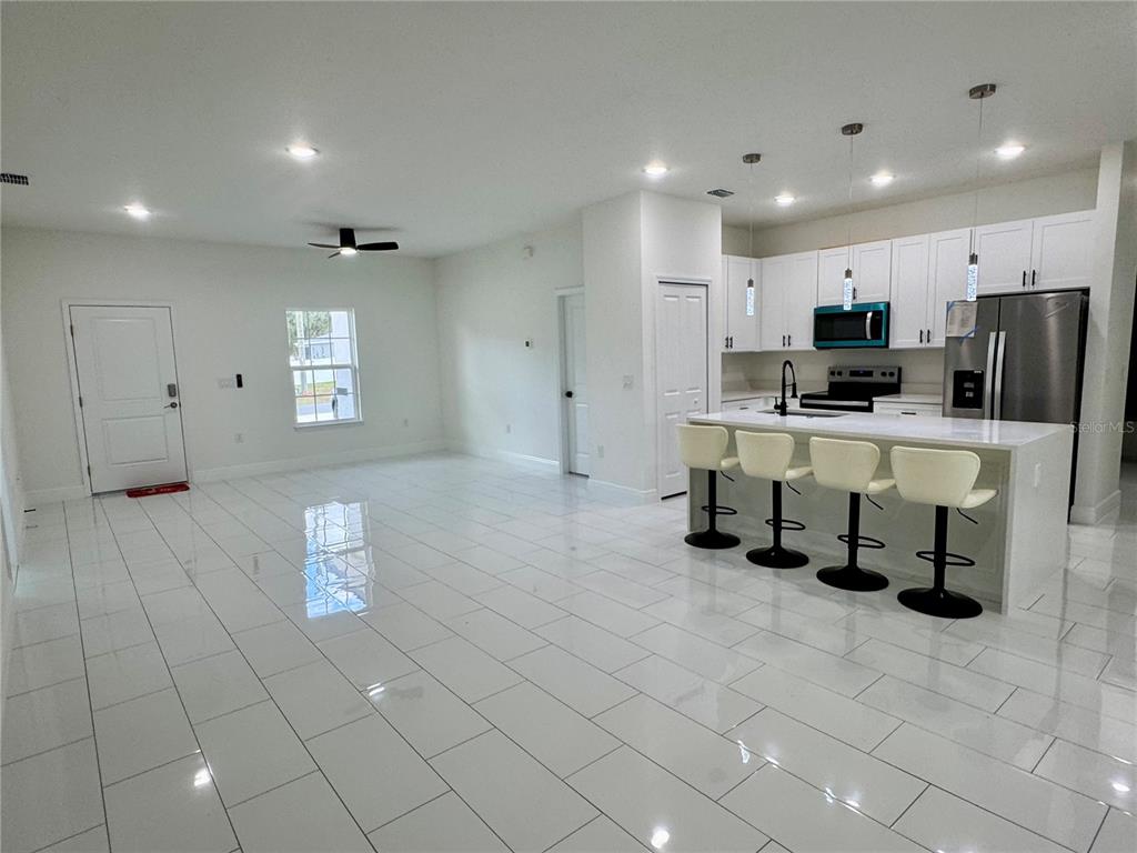 12970 Southwest 43rd Ave Road Ocala, FL 34473 - Photo 18 of 44 a large white kitchen with kitchen island granite countertop a stove a sink a refrigerator and white cabinets with wooden floor