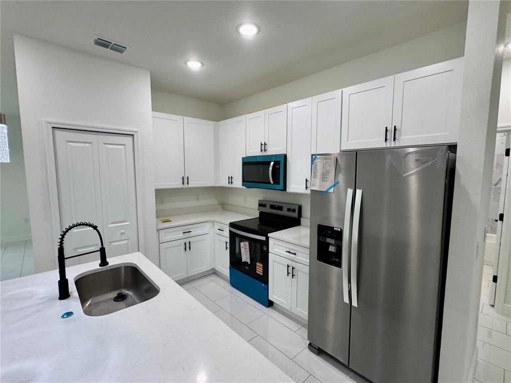 12970 Southwest 43rd Ave Road Ocala, FL 34473 - Photo 39 of 44 a kitchen with a refrigerator sink and white cabinets