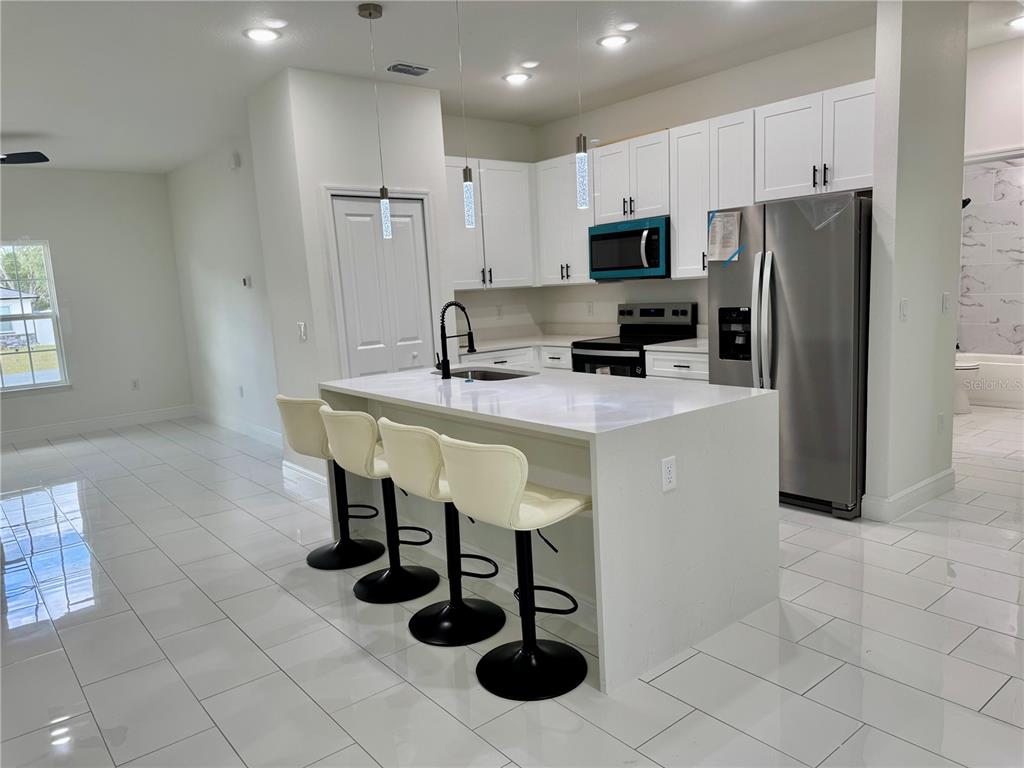 12970 Southwest 43rd Ave Road Ocala, FL 34473 - Photo 40 of 44 a kitchen with stainless steel appliances granite countertop a sink a stove a microwave a counter and cabinets
