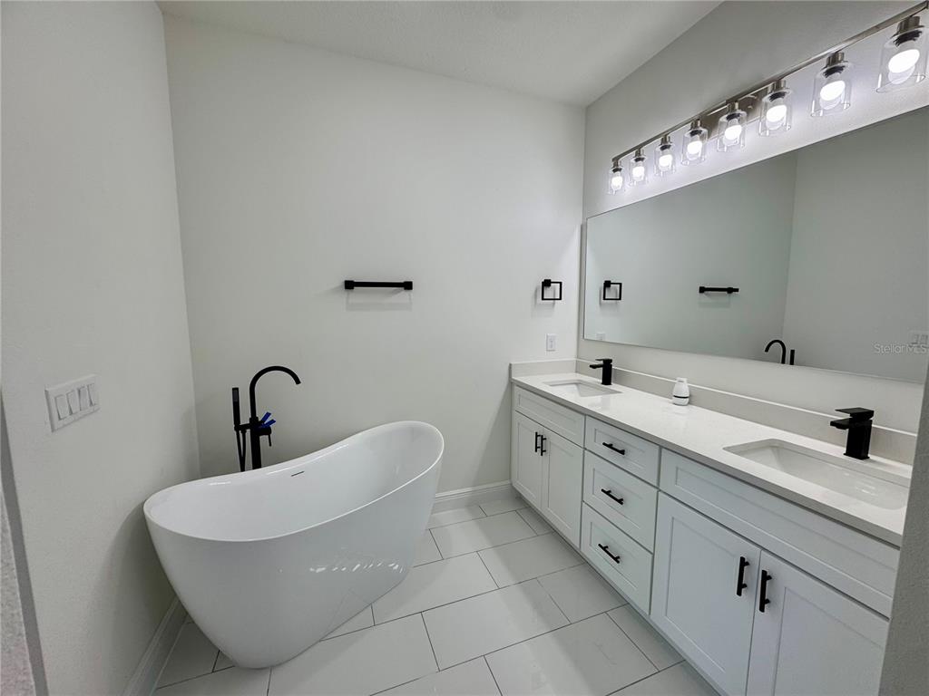 12970 Southwest 43rd Ave Road Ocala, FL 34473 - Photo 8 of 44 a bathroom with a double vanity sink a large mirror and bathtub