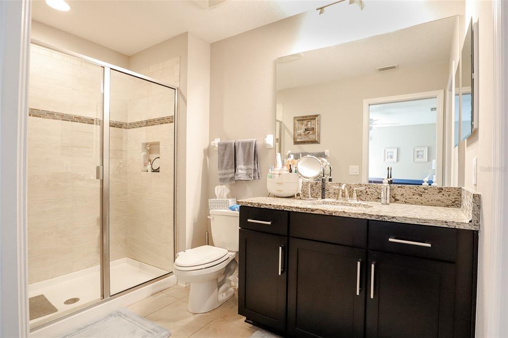 12556 Rangeland Boulevard Odessa, FL 33556 - Photo 25 of 27 a bathroom with a granite countertop sink toilet a mirror and shower