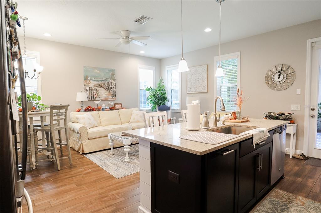 12556 Rangeland Boulevard Odessa, FL 33556 - Photo 5 of 27 a living room with a kitchen island furniture a chandelier a sink and a large mirror