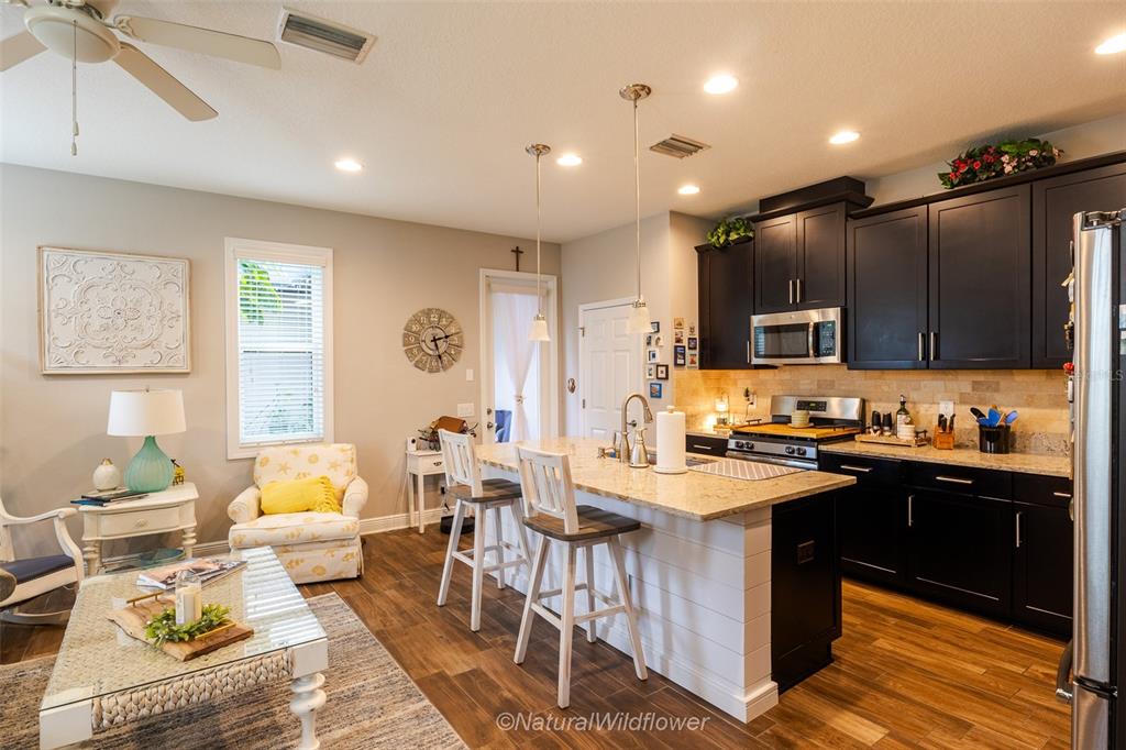 12556 Rangeland Boulevard Odessa, FL 33556 - Photo 6 of 29 a kitchen with stainless steel appliances kitchen island granite countertop a sink dishwasher a stove a dining table and chairs with wooden floor