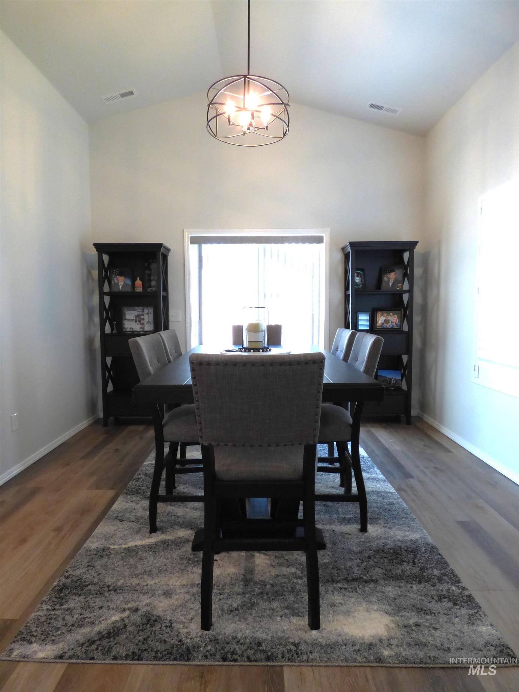 2708 East Buckaroo Drive Kuna, ID 83634 - Photo 9 of 48 Vaulted ceiling featuring a contemporary chandelier, wood-finish flooring, and built-in shelving units