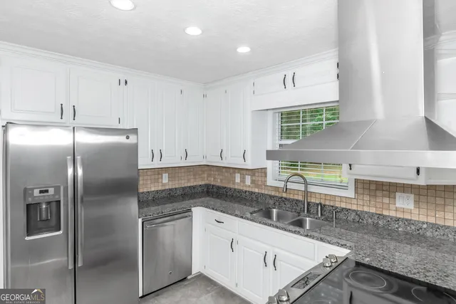 a kitchen with stainless steel appliances granite countertop a sink a stove and a refrigerator