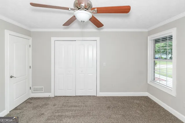 an empty room with windows and fan