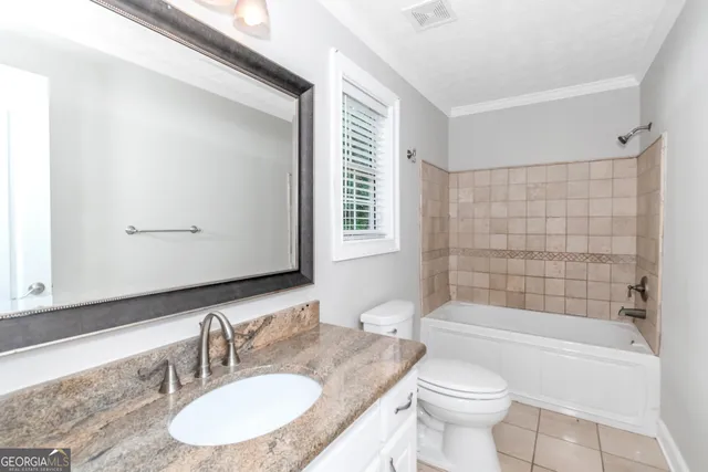 a bathroom with a granite countertop sink toilet mirror and bathtub