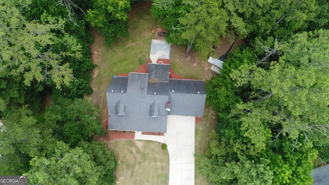 an aerial view of a house with outdoor space and trees all around