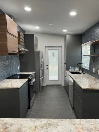 a kitchen with granite countertop a sink stove and refrigerator