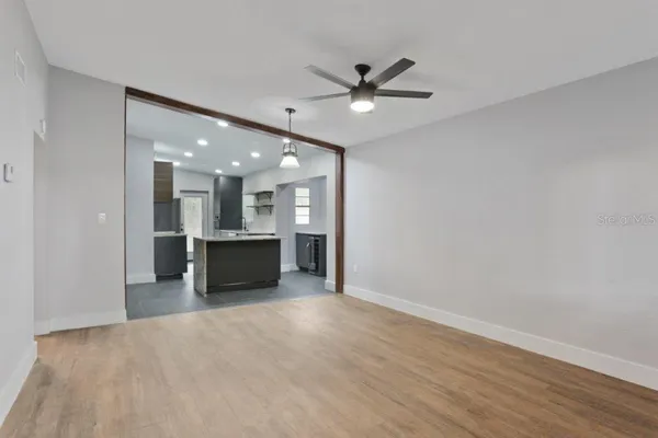 a view of a big room with wooden floor and a kitchen