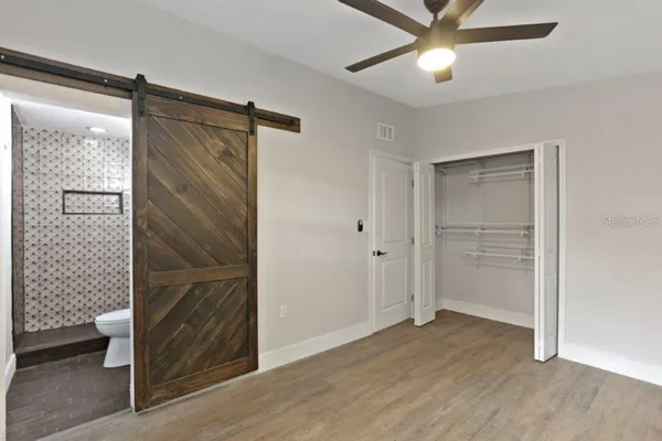 a view of empty room with wooden floor and fan