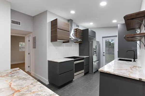 a kitchen with stainless steel appliances kitchen island granite countertop a refrigerator and a stove top oven