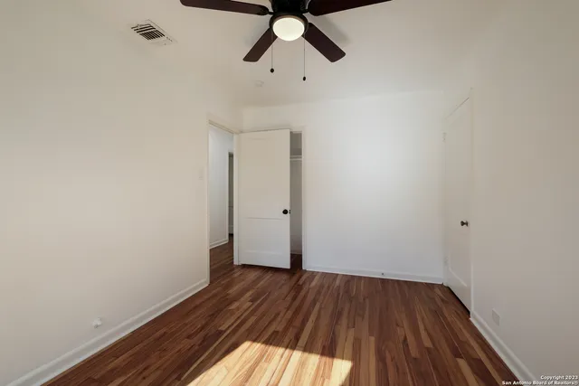 a view of empty room with wooden floor and ceiling fan