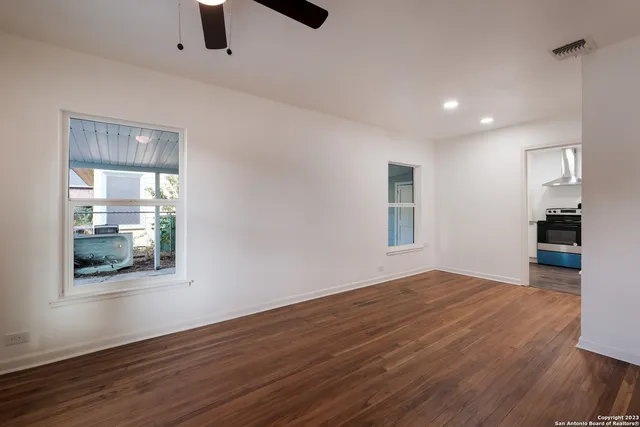 a view of an empty room with wooden floor and a window