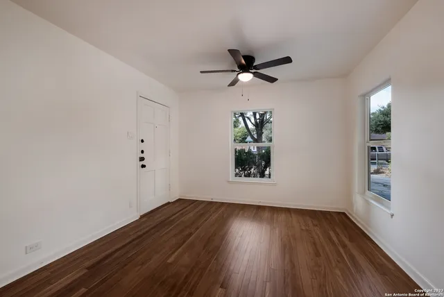 an empty room with wooden floor and windows
