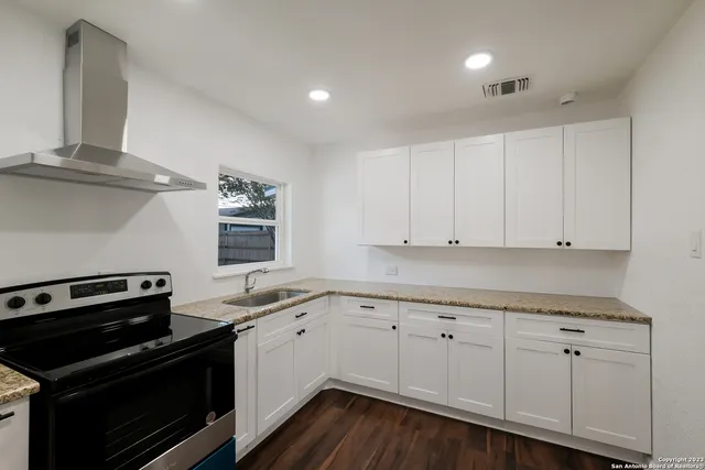 a kitchen with granite countertop white cabinets and stainless steel appliances
