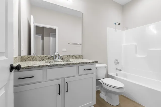 a bathroom with a granite countertop toilet sink and mirror