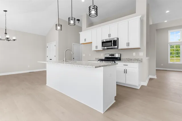 a kitchen with stainless steel appliances granite countertop a sink a stove a refrigerator cabinets and a window