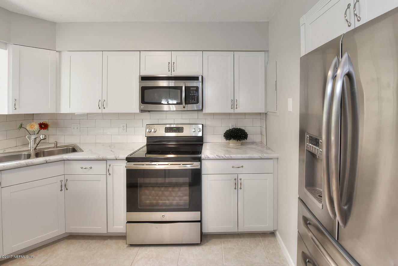 4640 Tanbark Road Jacksonville, FL 32210 - Photo 8 of 28 a kitchen with white cabinets and stainless steel appliances