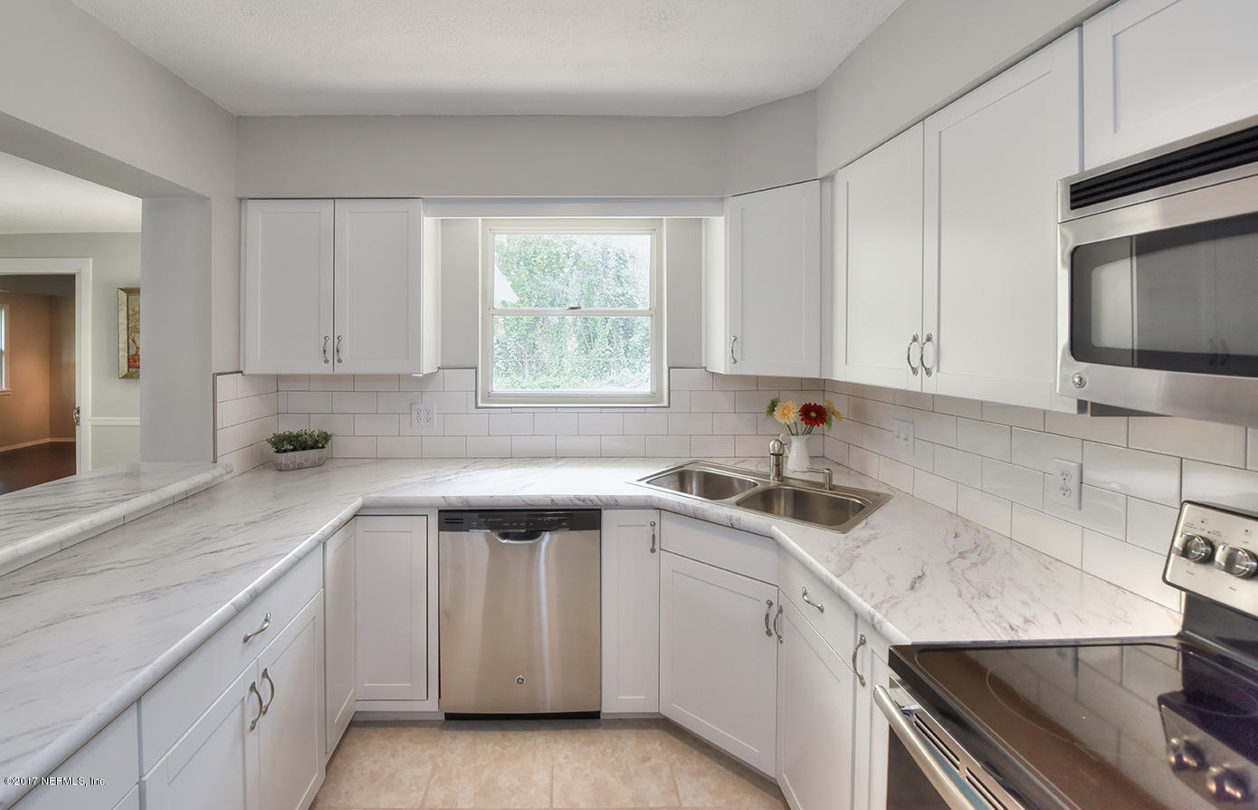 4640 Tanbark Road Jacksonville, FL 32210 - Photo 10 of 28 a kitchen with a sink dishwasher and white cabinets with wooden floor