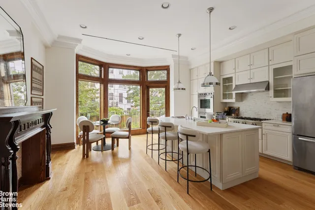 a open kitchen with stainless steel appliances granite countertop a stove a refrigerator a kitchen island a dining table and chairs with wooden floor