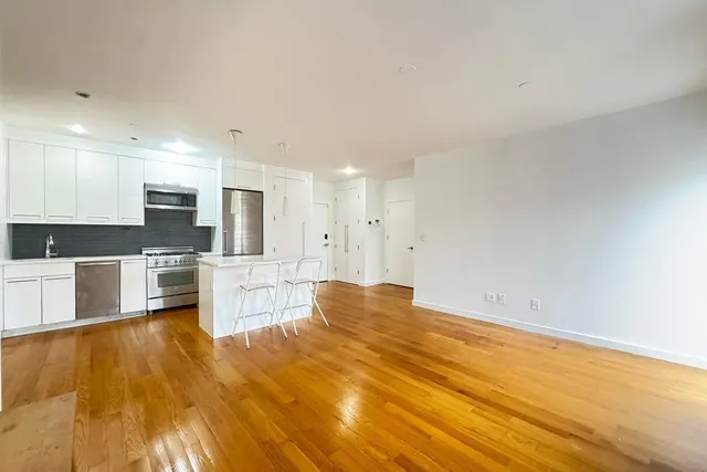 a view of kitchen with kitchen island wooden floor and stainless steel appliances
