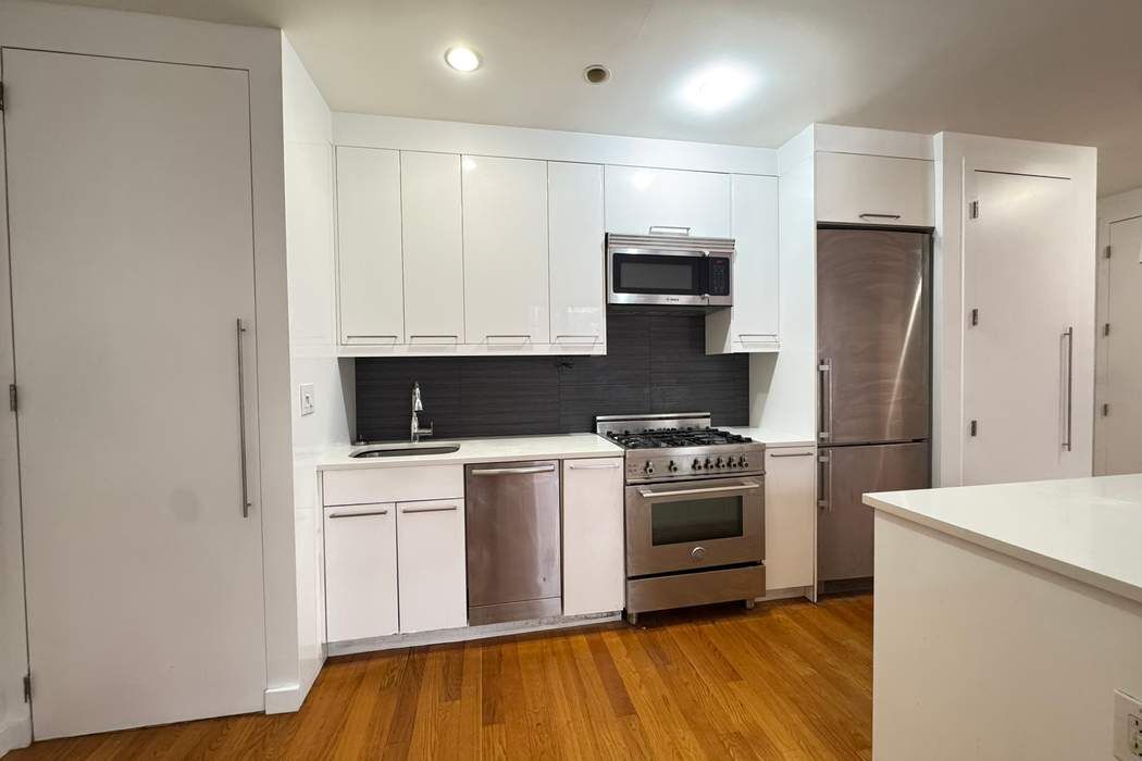 51 East 128th Street, Unit 6A Manhattan, NY 10035 - Photo 4 of 14 a kitchen with stainless steel appliances granite countertop a stove a sink and a refrigerator