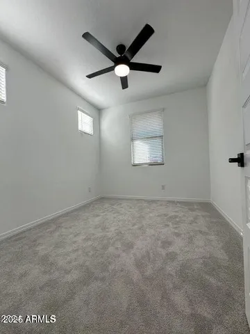 en empty room with windows and ceiling fan
