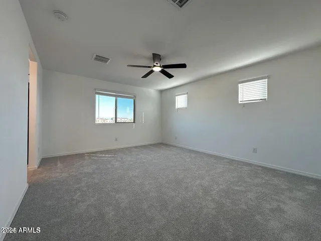an empty room with windows and ceiling fan