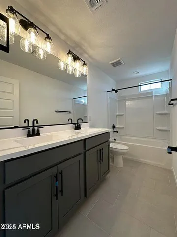 a bathroom with a double vanity sink a toilet and a bathtub
