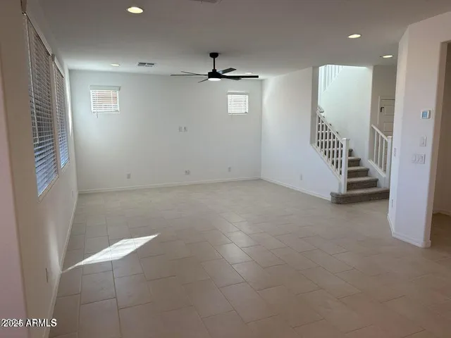 an empty room with staircase and ceiling fan