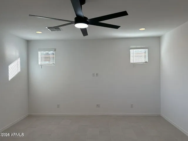 an empty room with a ceiling fan and window