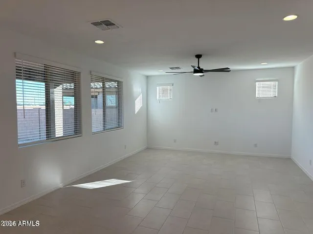 an empty room with windows and ceiling fan