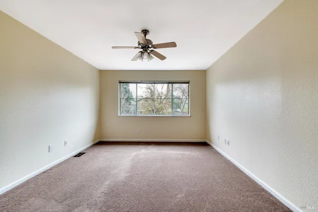 an empty room with windows and fan