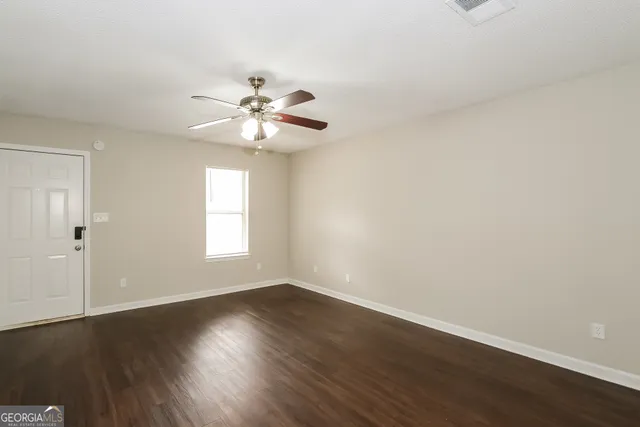 a view of empty room with wooden floor and fan