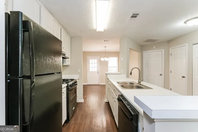 an empty room with wooden floor chandelier fan and windows