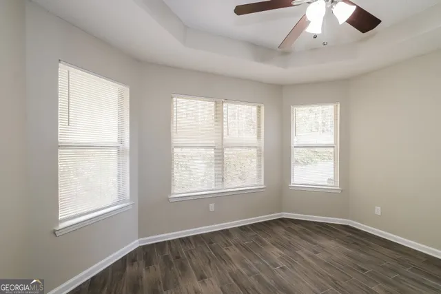 a view of an empty room with window and wooden floor