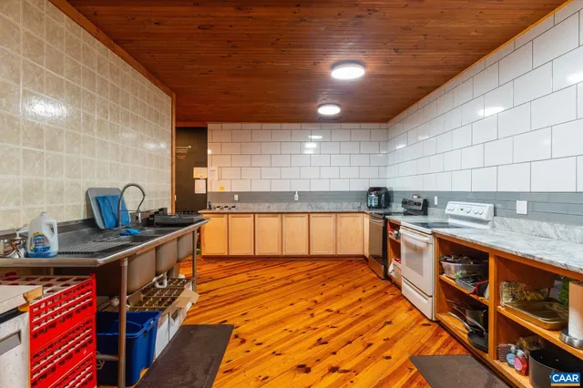 a kitchen with stainless steel appliances granite countertop a refrigerator a sink a stove and white cabinets with wooden floor