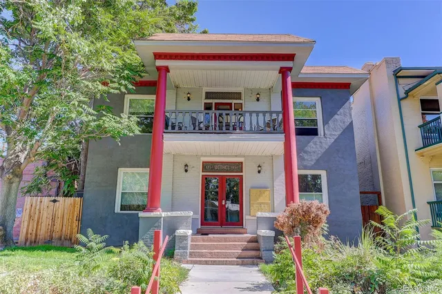 a view of a house with potted plants and a large tree