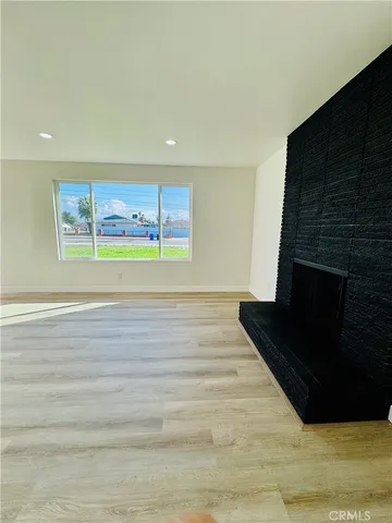 a view of an empty room with wooden floor and a fireplace