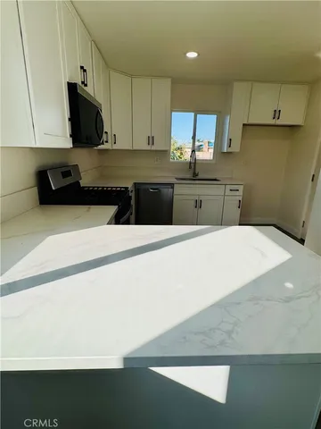 a kitchen with stainless steel appliances a refrigerator sink and white cabinets