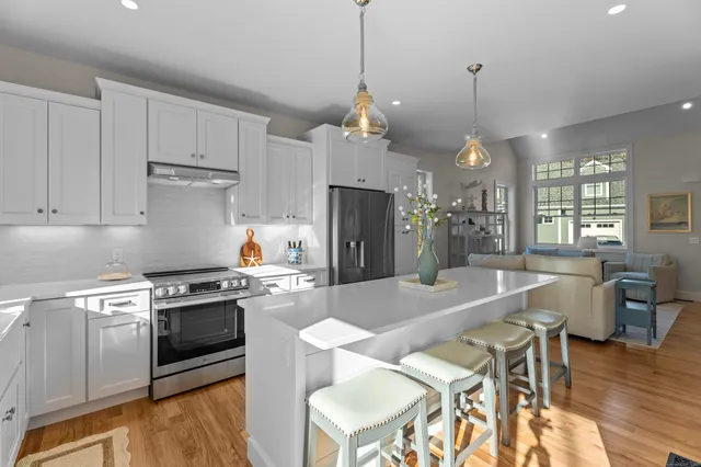 a kitchen with stainless steel appliances granite countertop a stove a sink a refrigerator a stove a dining table and chairs with wooden floor