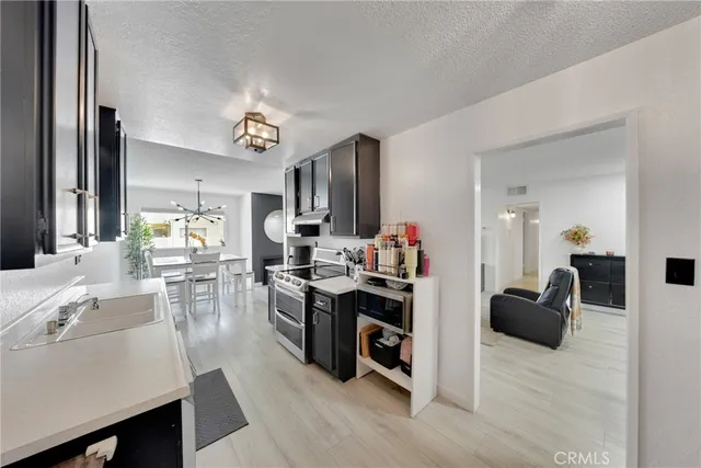 a view of kitchen with kitchen island stainless steel appliances refrigerator stove dining table and chairs