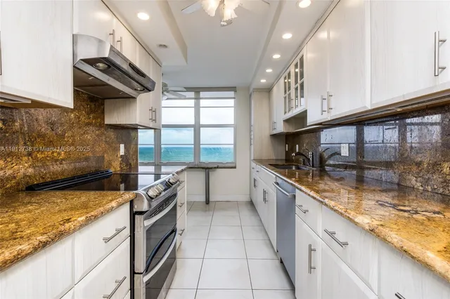 a kitchen with granite countertop white cabinets and sink