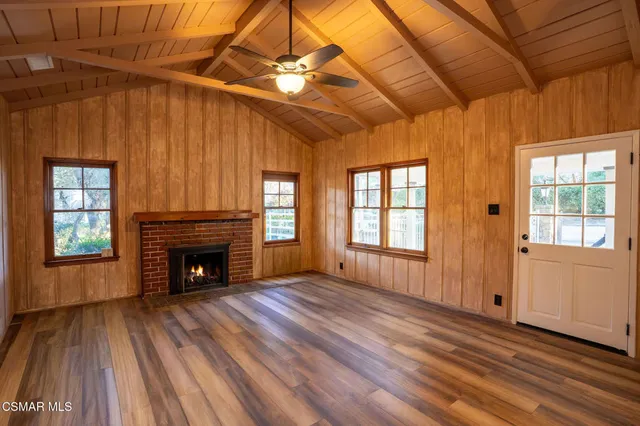 a view of an empty room with wooden floor fireplace and a window