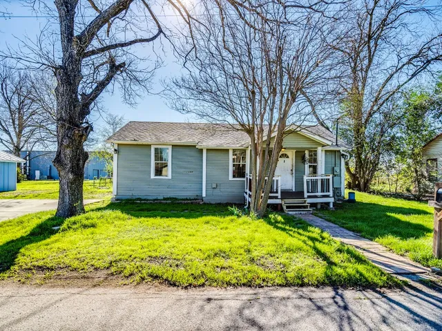 a view of a house with a yard patio and a tree