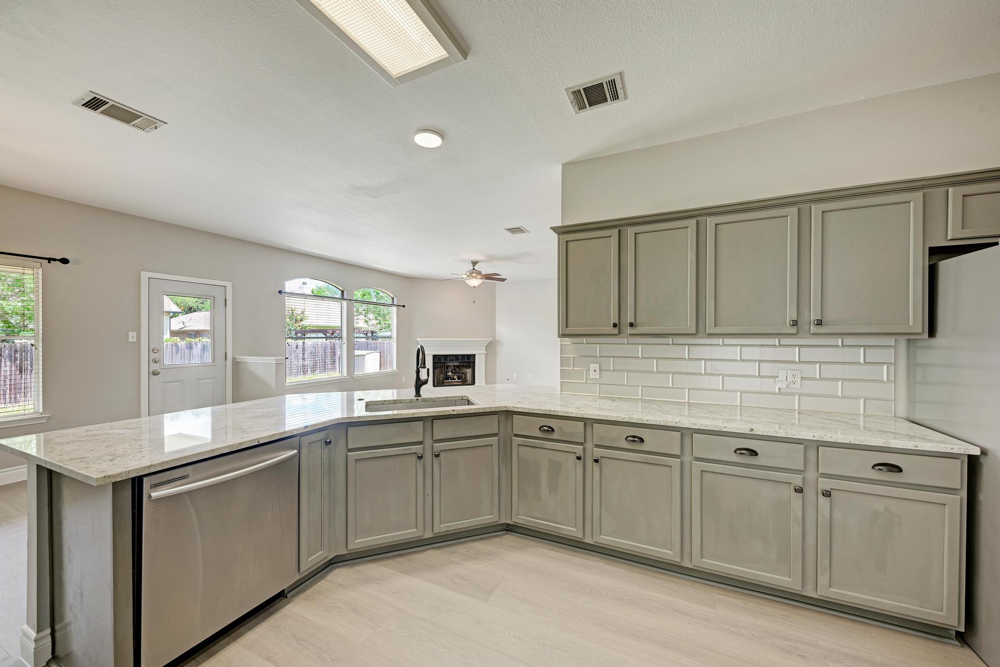 4408 Tello Path Austin, TX 78749 - Photo 17 of 38 Kitchen featuring dishwasher, gray cabinets, a ceiling fan, a peninsula, and decorative backsplash